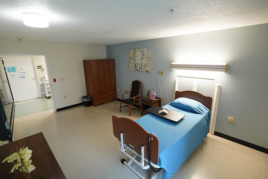 Bed with overbed table and chair in private room- Arbors at Sylvania