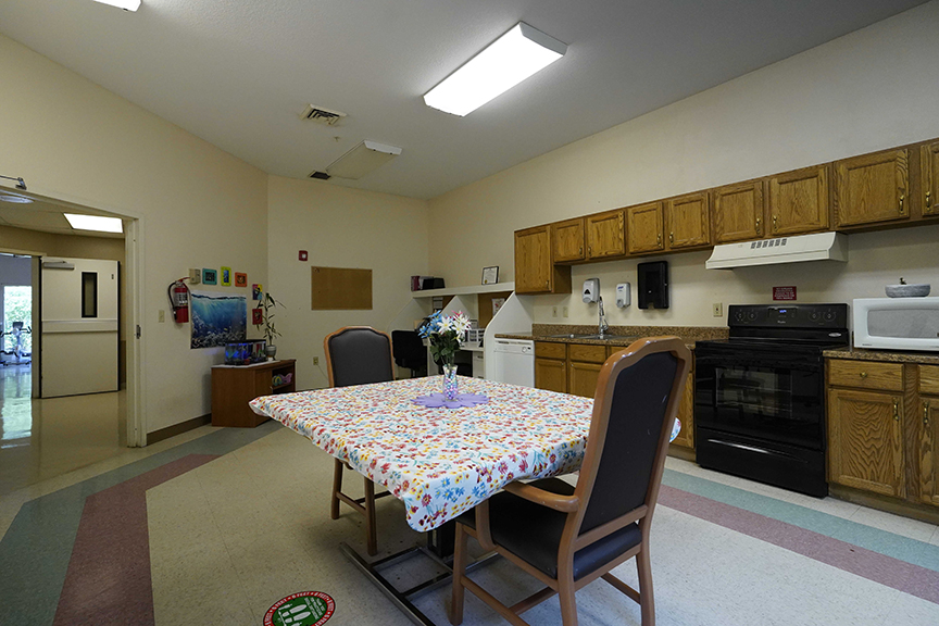 Kitchenette and table set with flower vase in resident lounge- Arbors at Sylvania